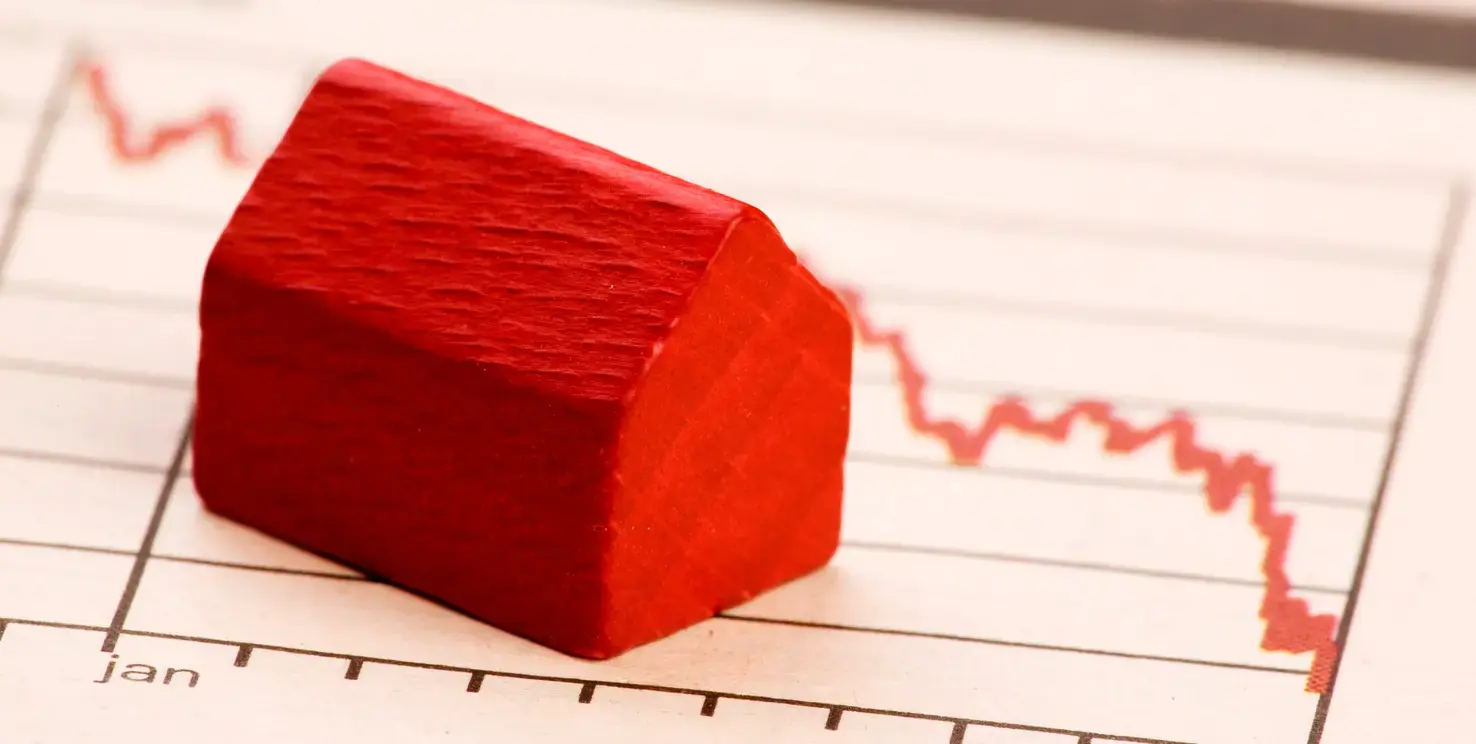 Red house model on a declining chart illustrating closing costs for a California home seller