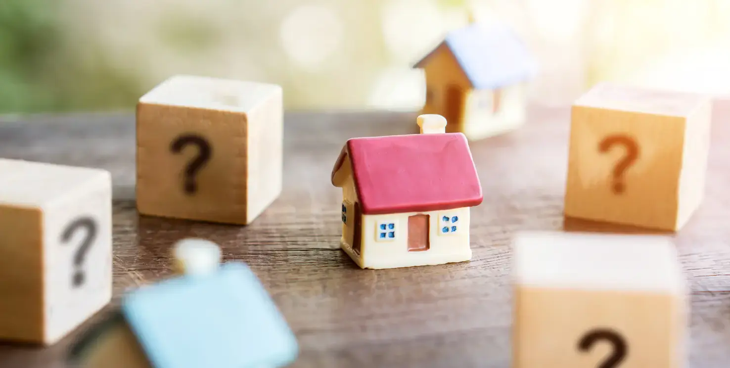Mini house surrounded by question mark blocks, representing questions to ask a Realtor when selling your house