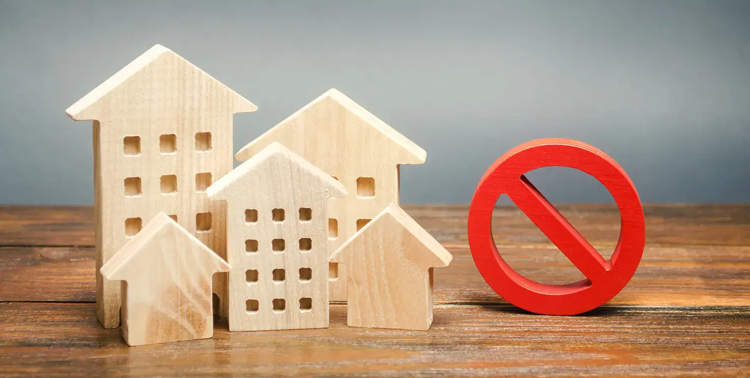 Wooden house models beside a red no symbol, representing what not to fix when selling a house