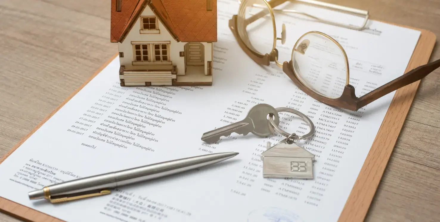 House model, keys, and paperwork representing selling a house in a trust
