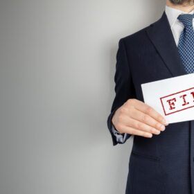 Male Realtor holding a sign that says 'Fired'